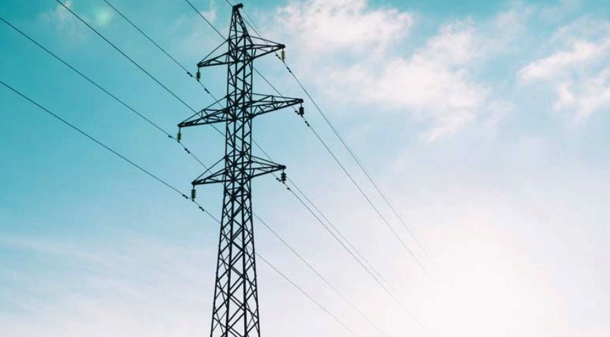 tall power lines with a background of blue sky and fluffy white clouds